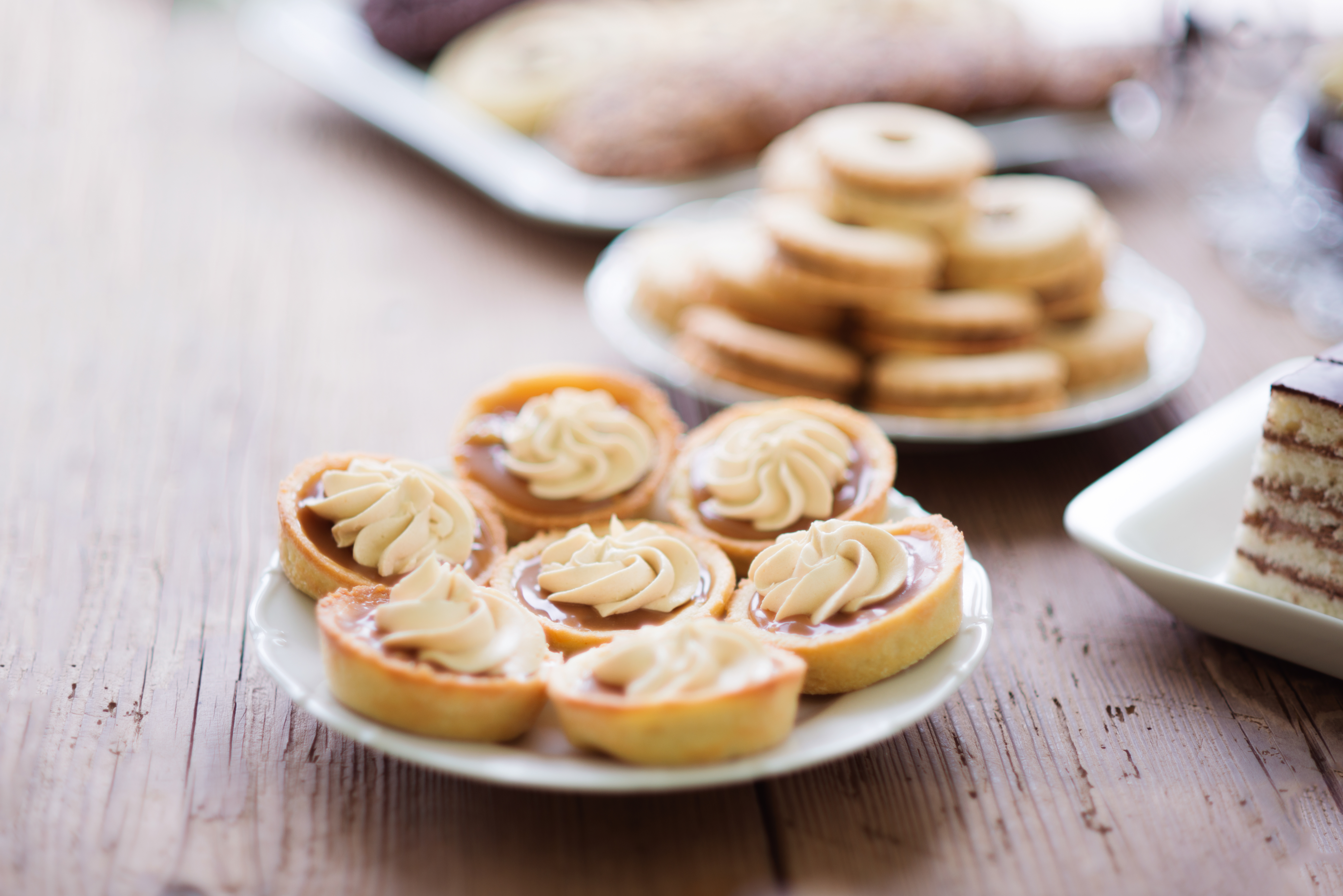 Table with tarts with jam and cream, wooden background.